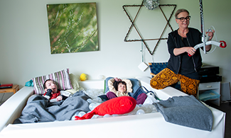 Två personer ligger i ett bollhav och en person står bredvid 