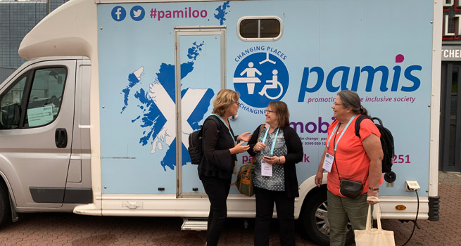 Birgitta och Ann-Kristin tillsammans med en av de som arbetar i organisationen Pamis får höra om den transportabla toaletten.