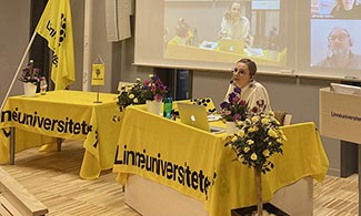 Bild på Frida Andersson som sitter vid Linnéuniversitets bord och sitter i ett digitalt möte.