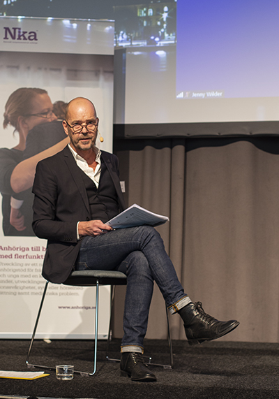 Robert Öberg sitter på en stol på scenen. 